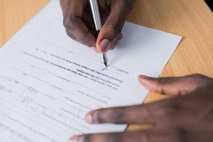 En hand håller en penna och skriver på ett kontrakt