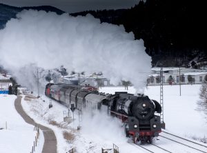 Ett tåg kör i snö, omgivet av rök